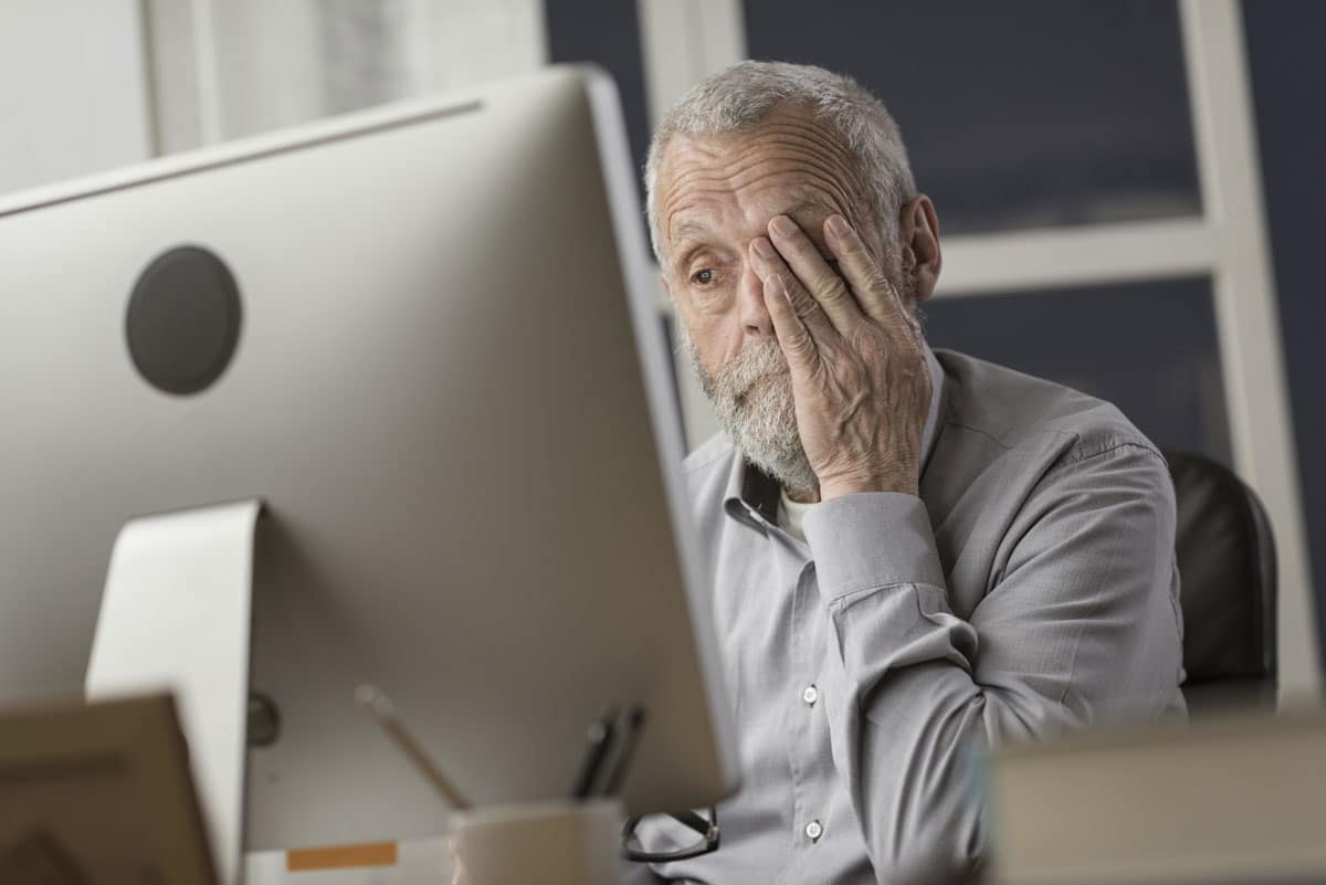 Cogntitive Impairment - senior looks at computer screen with frustration